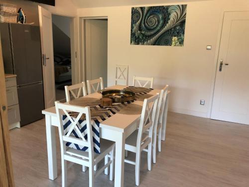 a white dining room table with white chairs and a painting at Comfort Zone Ostróda Ruś Mała in Ostróda