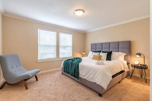a bedroom with a large bed and a blue chair at Modern home, Four bedrooms, King Beds in Tigard