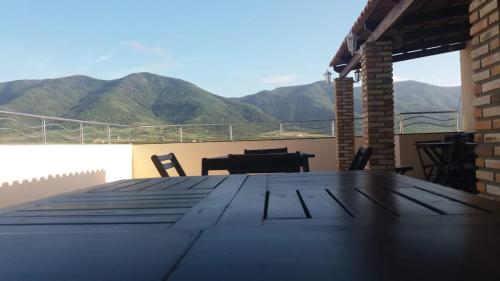a large wooden table on a balcony with mountains in the background at Seller Hotel in Sobral