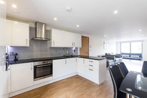 a kitchen with white cabinets and a table and a couch at Zone 1 Bright and Modern 3 Bed Apt Hyde Park Central London in London