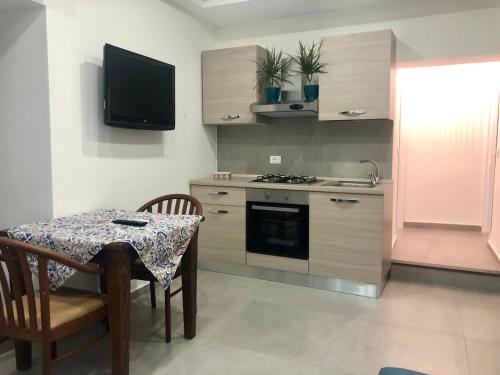 eine Küche mit einem Tisch und einem TV an der Wand in der Unterkunft CIVITAS 2 in Catania