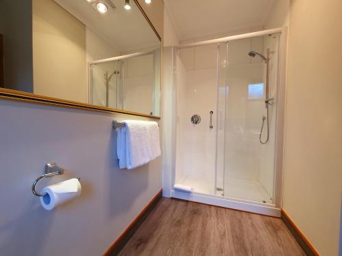 a bathroom with a shower and a toilet paper roll at Fitzherbert Castle Motel in Palmerston North