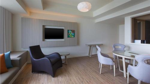 a living room with chairs and a table and a tv at Mercure Penang Beach in George Town