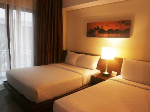 a hotel room with two beds and a lamp at Crown Regency Beach Resort in Boracay