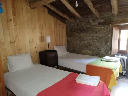 2 camas en una habitación con paredes de madera en Casa de Cima, en Lousã
