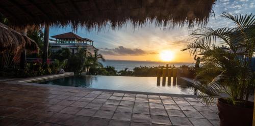 a swimming pool with a sunset in the background at Casa de los Sueños Hotel Boutique in Isla Mujeres