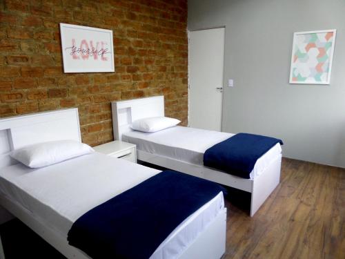 2 camas en una habitación con una pared de ladrillo en Visto Hostel, en São Paulo