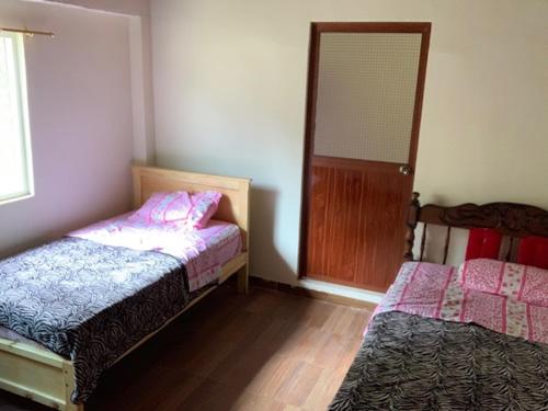 a room with two beds and a door with a window at Candurumy Lodge in Tena