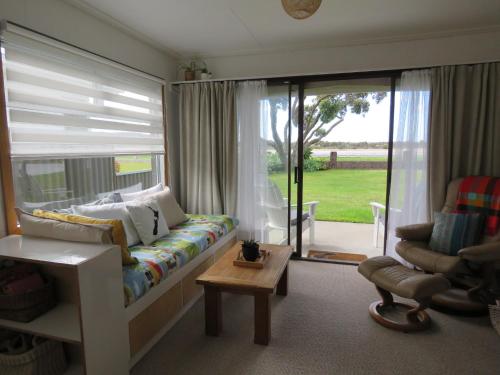 a living room with a couch and a chair at Pohutukawa Bach in Whangarei