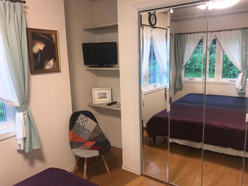 a bedroom with a bed and a chair and windows at Himawari in Minami Aso