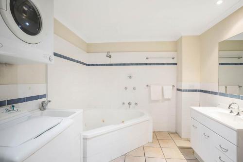 a white bathroom with a tub and a sink at Sails Luxury Apartments Merimbula in Merimbula