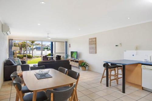 a kitchen and living room with a table and chairs at Sails Luxury Apartments Merimbula in Merimbula