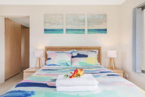 a bedroom with a bed with towels and two lamps at Sails Luxury Apartments Merimbula in Merimbula