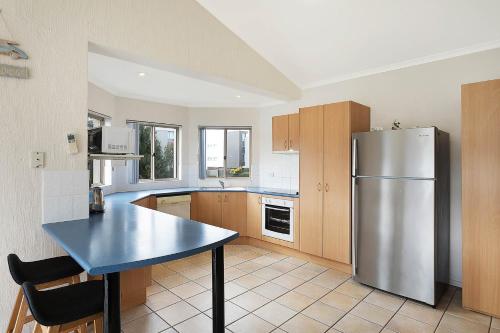 a kitchen with a stainless steel refrigerator and a table at Sails Luxury Apartments Merimbula in Merimbula