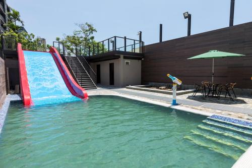 a water slide in a pool with a table and an umbrella at Chuang-tang Spring Spa Hotel in Jiaoxi