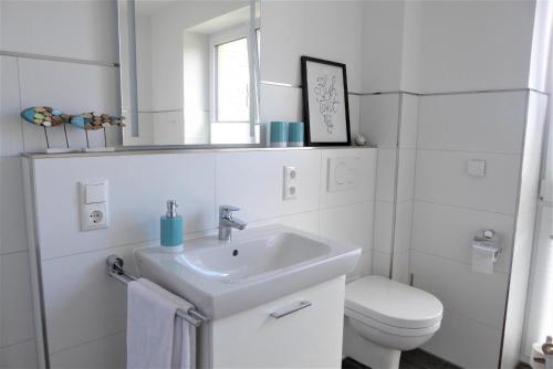 Baño blanco con lavabo y aseo en Haus Fehnhuus, Am Alten Deich 11a, en Dangast