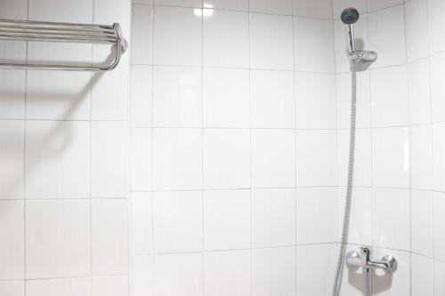 a white tiled bathroom with a shower at Modern 2BR Apartment at Mekarwangi Square Cibaduyut By Travelio in Bandung