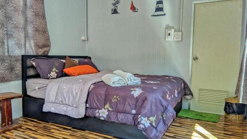 a bedroom with a purple bed with towels on it at Baan Suchanuch in Don Sak