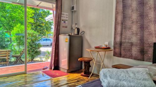 a kitchen with a refrigerator next to a sliding glass door at Baan Suchanuch in Don Sak