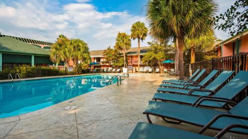 a row of lounge chairs next to a swimming pool at Best Western Charleston Inn in Charleston