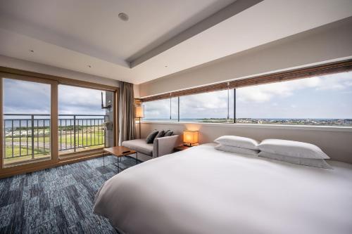 a bedroom with a large bed and large windows at Ktree Jeju Seongsan Hotel in Seogwipo