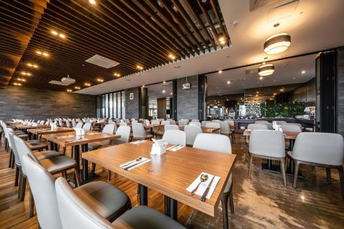 restauracja z drewnianymi stołami i białymi krzesłami w obiekcie Golden Tulip Jeju Seongsan Hotel w mieście Seogwipo