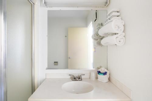 Baño blanco con lavabo y espejo en Days Inn by Wyndham New Philadelphia, en New Philadelphia
