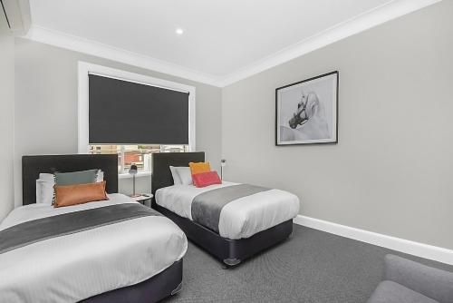 a bedroom with two beds and a couch in it at Horse and Jockey Hotel Homebush in Sydney