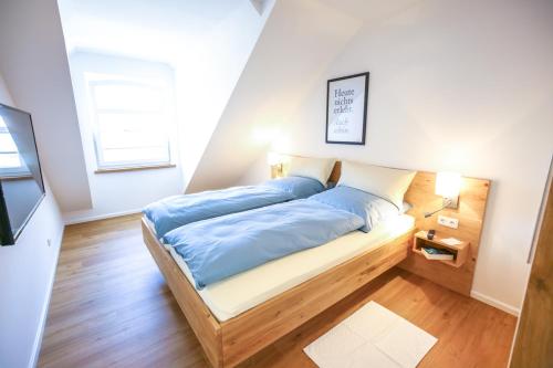 een bed met blauwe lakens in een kleine kamer bij Boarding3 - Wohnen auf Zeit in Aurich