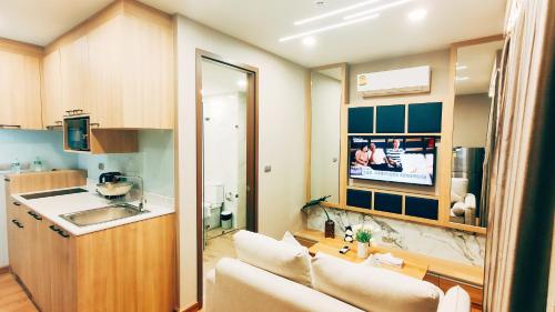 a kitchen and a living room with a couch and a tv at Pleasant Chiangmai in Chiang Mai