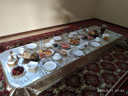 a table topped with plates and bowls of food at Xurshidabonu Guest House in Khiva