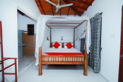 um quarto com uma cama de dossel e almofadas vermelhas em Happy Night Holiday Inn em Unawatuna