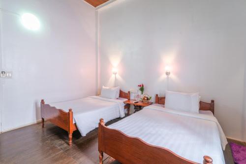 a room with two beds and a table in it at Five Rose Siem Reap Hostel in Siem Reap