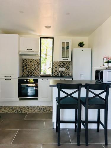 une cuisine avec des placards blancs et une table et des chaises noires dans l'établissement COTTAGE A LA FONTAINE DU CHENE, à Lancôme