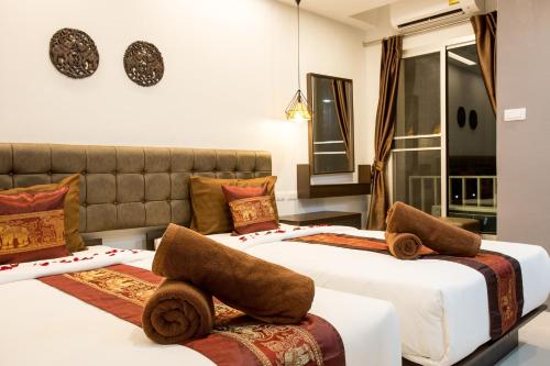 two beds in a hotel room with towels on them at Pongsakorn Boutique Resort -SHA Extra Plus in Lat Krabang