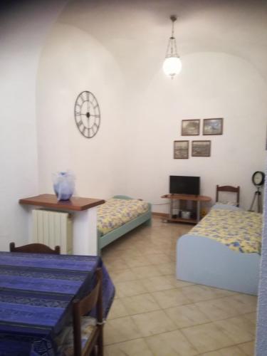 Zimmer mit 2 Betten, einem Tisch und einer Uhr in der Unterkunft Casa Margherita in Santo Stefano al Mare