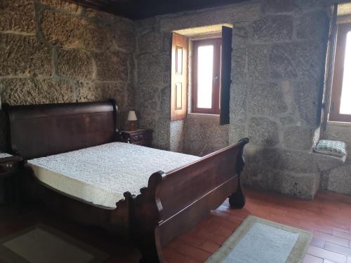 a bedroom with a bed in a stone wall at Casa da Eira - Castanheiras in Resende