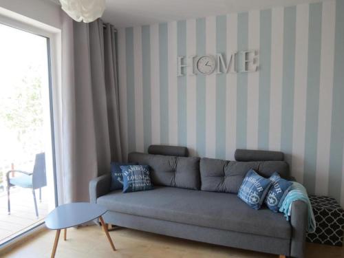 a living room with a couch and a sign that reads home at Apartament Siesta Sunny Spa in Kołobrzeg