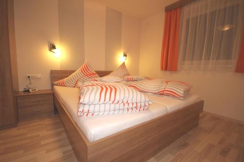 ナウダースにあるApart Carmenのベッドルーム1室(オレンジと白の枕が備わるベッド1台付)
