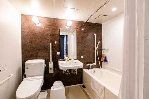 a bathroom with a toilet and a sink and a tub at Hotel Wing International Select Kumamoto in Kumamoto
