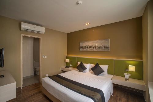 a bedroom with a large bed with a green wall at eL Hotel Jakarta in Jakarta