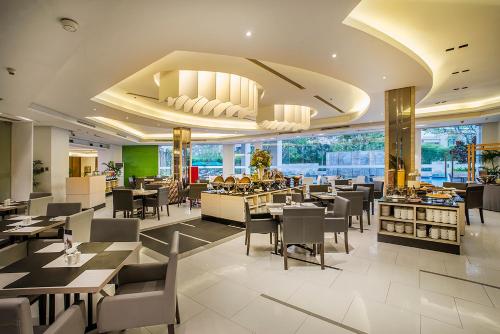 a dining room with tables and chairs in a restaurant at eL Hotel Jakarta in Jakarta