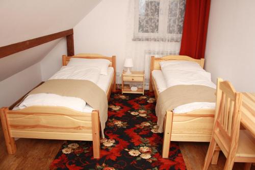 two twin beds in a room with a rug at Domek Uherce Mineralne in Uherce Mineralne (7)