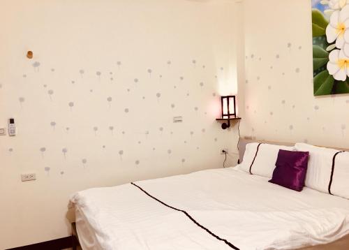 a bedroom with a white bed with a purple pillow at Home & Teak Homestay in Jinning