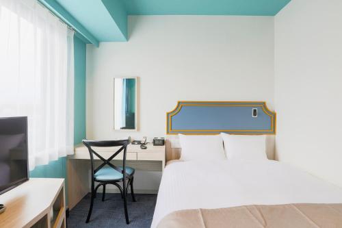a hotel room with a bed and a desk and a chair at Hotel Wing International Select Kumamoto in Kumamoto