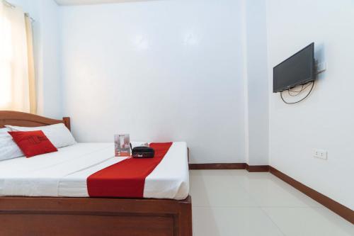 a bedroom with a bed with a tv on the wall at RedDoorz @ D Maagma Street in Kalibo