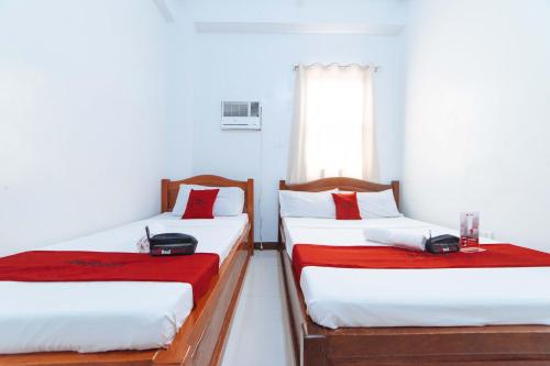 two twin beds in a room with a window at RedDoorz @ D Maagma Street in Kalibo
