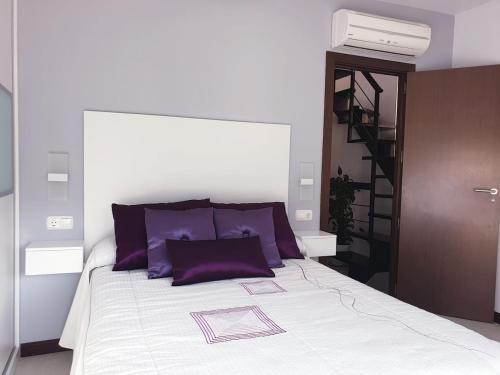 Un dormitorio con una cama con almohadas moradas y una escalera. en Bonita casa en Cotobro en Almuñécar