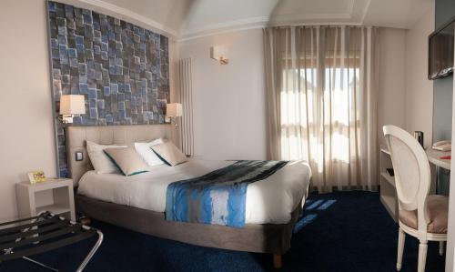 a hotel room with a large bed and a desk at Logis Hôtel Restaurant Le Fruitier in Villedieu-les-Poëles