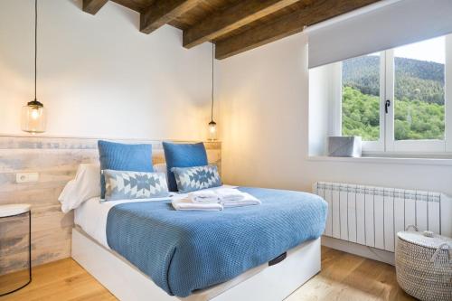 a bedroom with a blue bed and a window at Luderna - Dúplex con jardín des Treuetes in Gessa